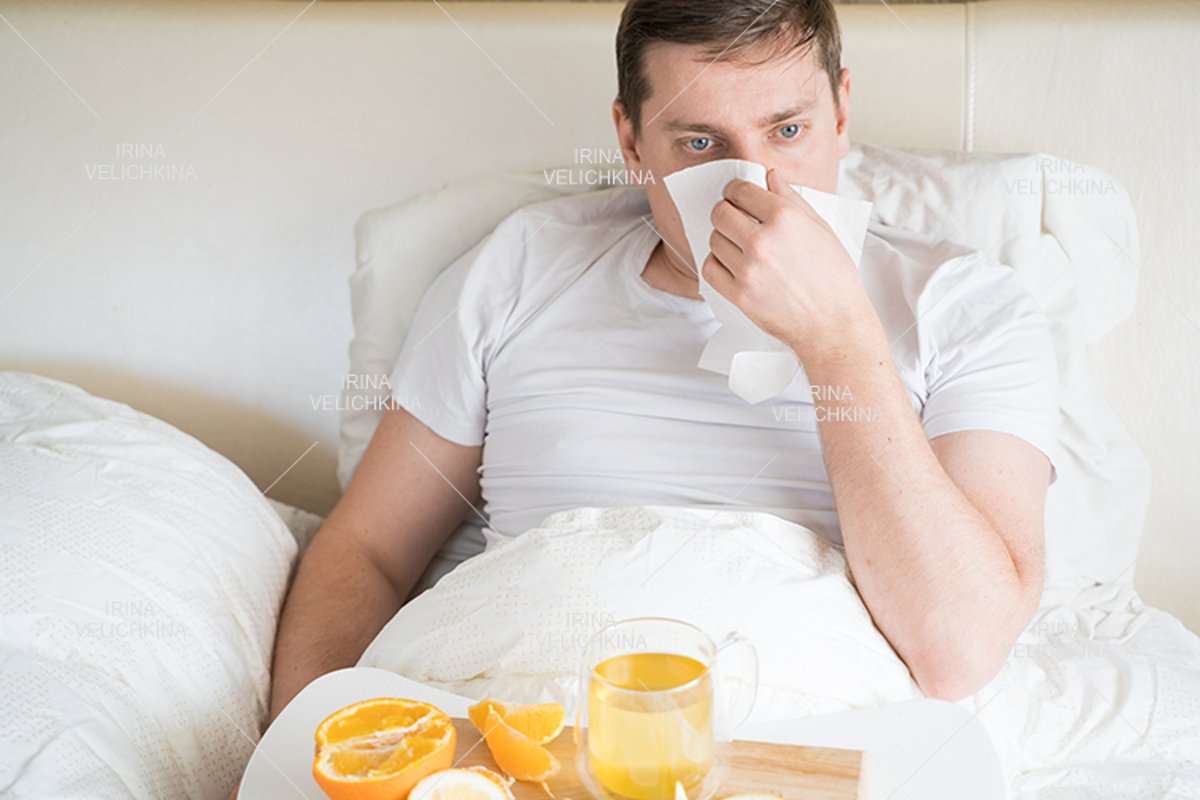Sick man in bed. Cup of flu drugs. Tea, orange,lemon,ginger example image 1