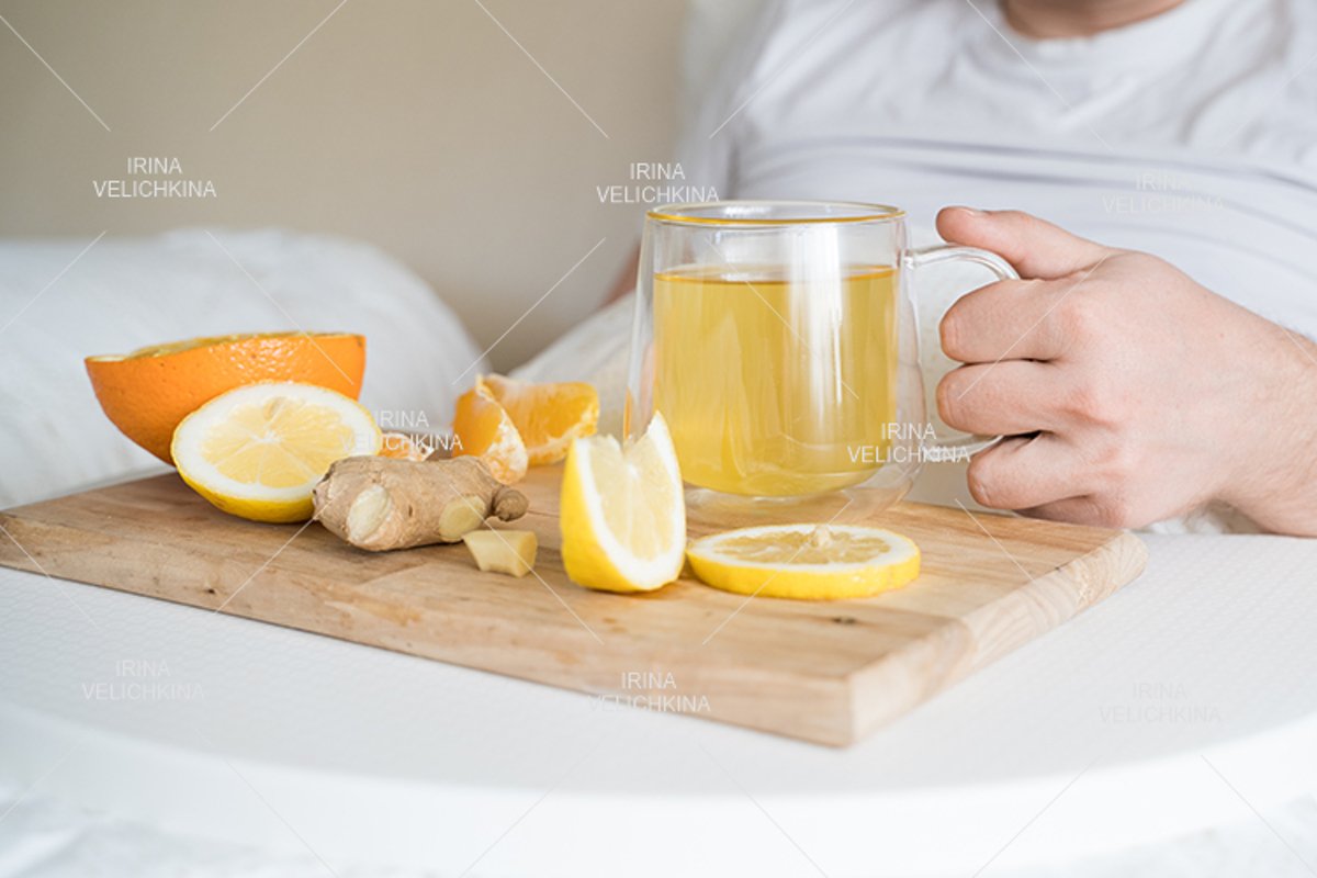 Sick man in bed. Cup of flu drugs. Tea, orange,lemon,ginger example image 1