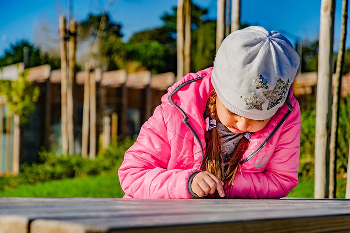 Sad little girl is on a bench in the park. example image 1