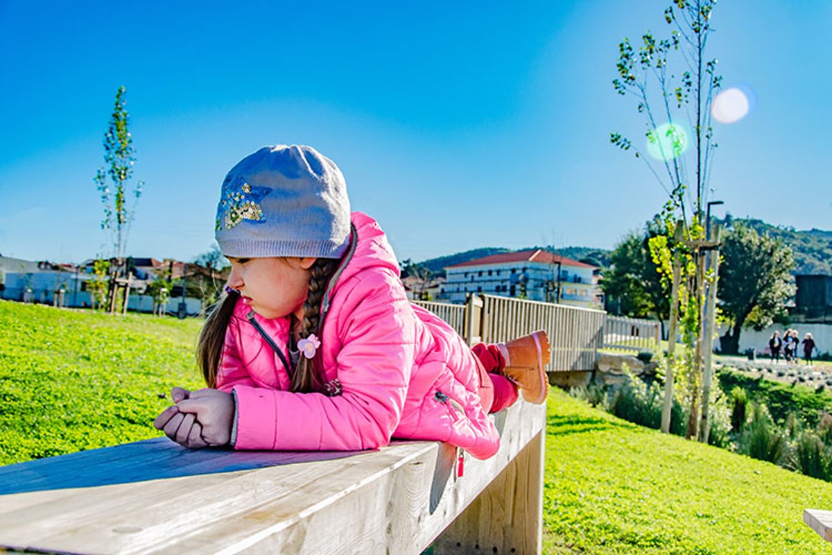 Sad little girl is on a bench in the park. example image 1
