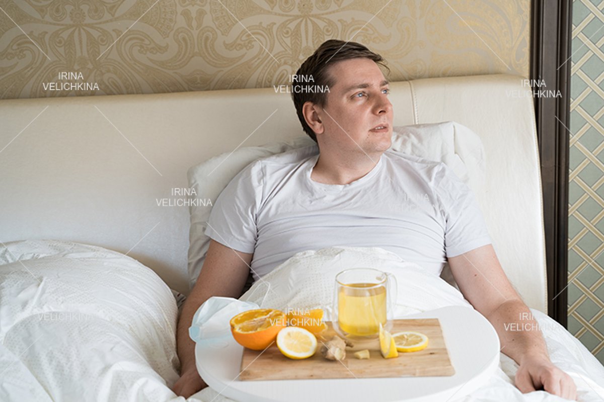 Sick man in bed. Cup of flu drugs. Tea, orange,lemon,ginger example image 1