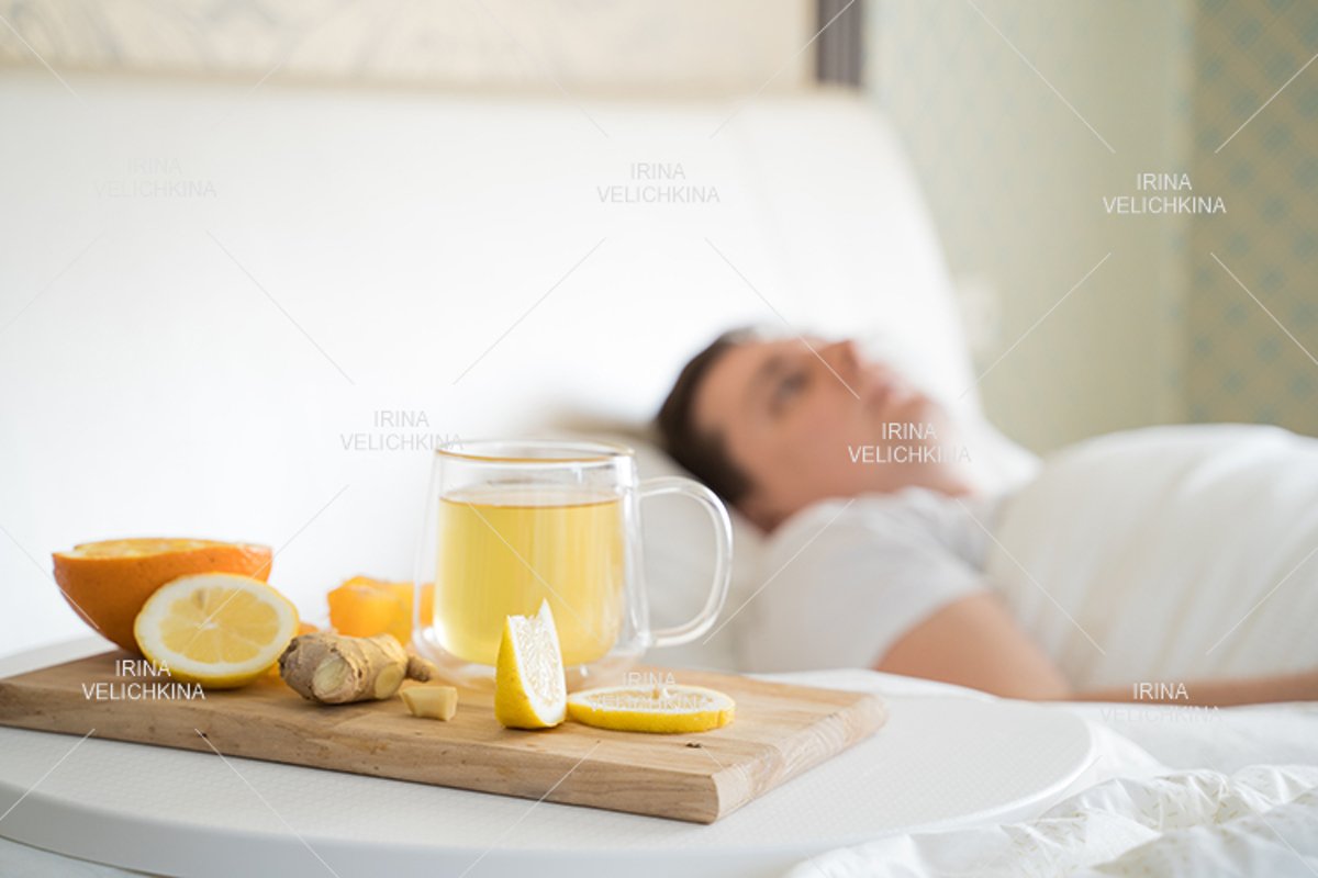 Sick man in bed. Cup of flu drugs. Tea, orange,lemon,ginger example image 1