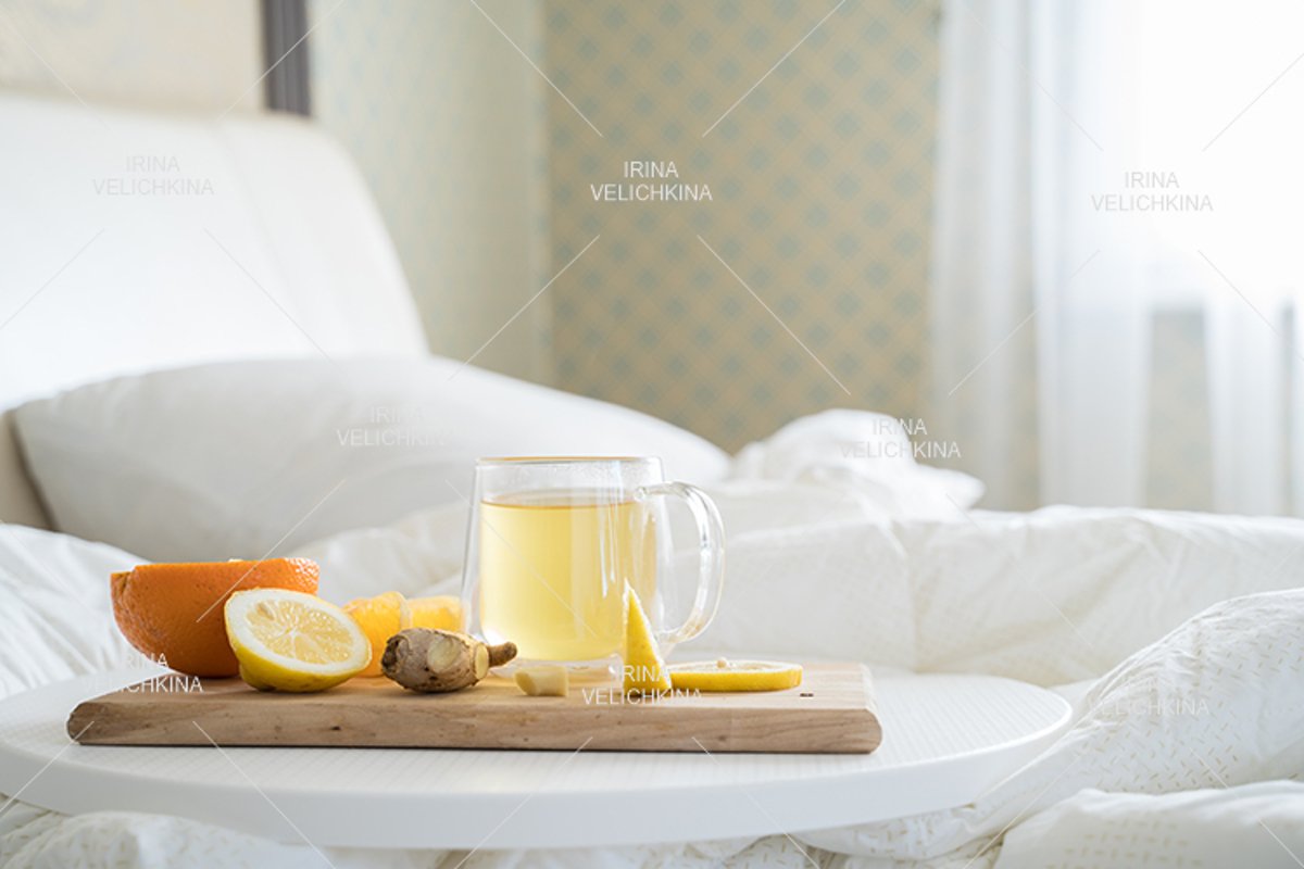 Cup of tea,orange,lemon,ginger in bed.Self treatment for flu example image 1