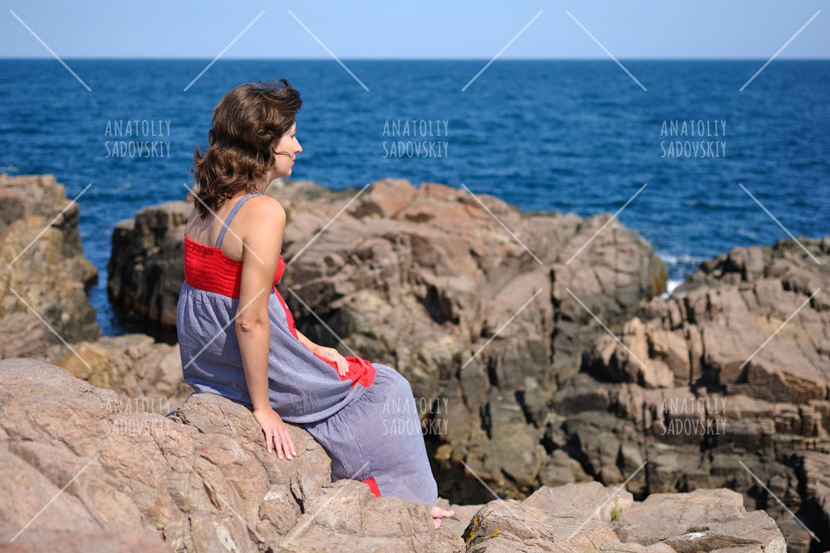 Woman sitting on rock near sea example image 1