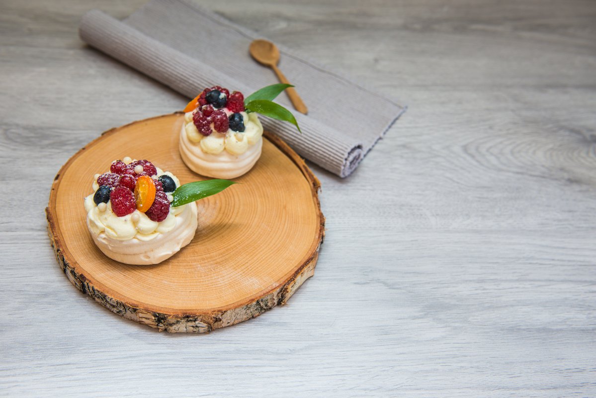 Pavlova meringue desert cake with cream and small fruits example image 1