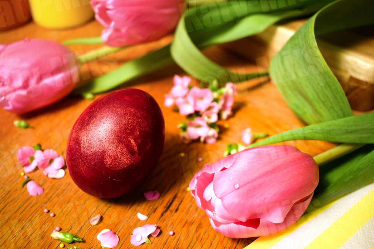 Easter eggs on a wooden table with pink flowers and petals. example image 1