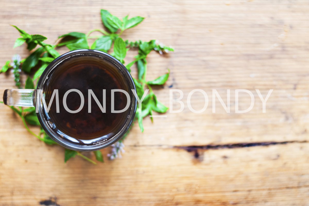 Black tea in a transparent cup with herbs on a wooden backgr example image 1