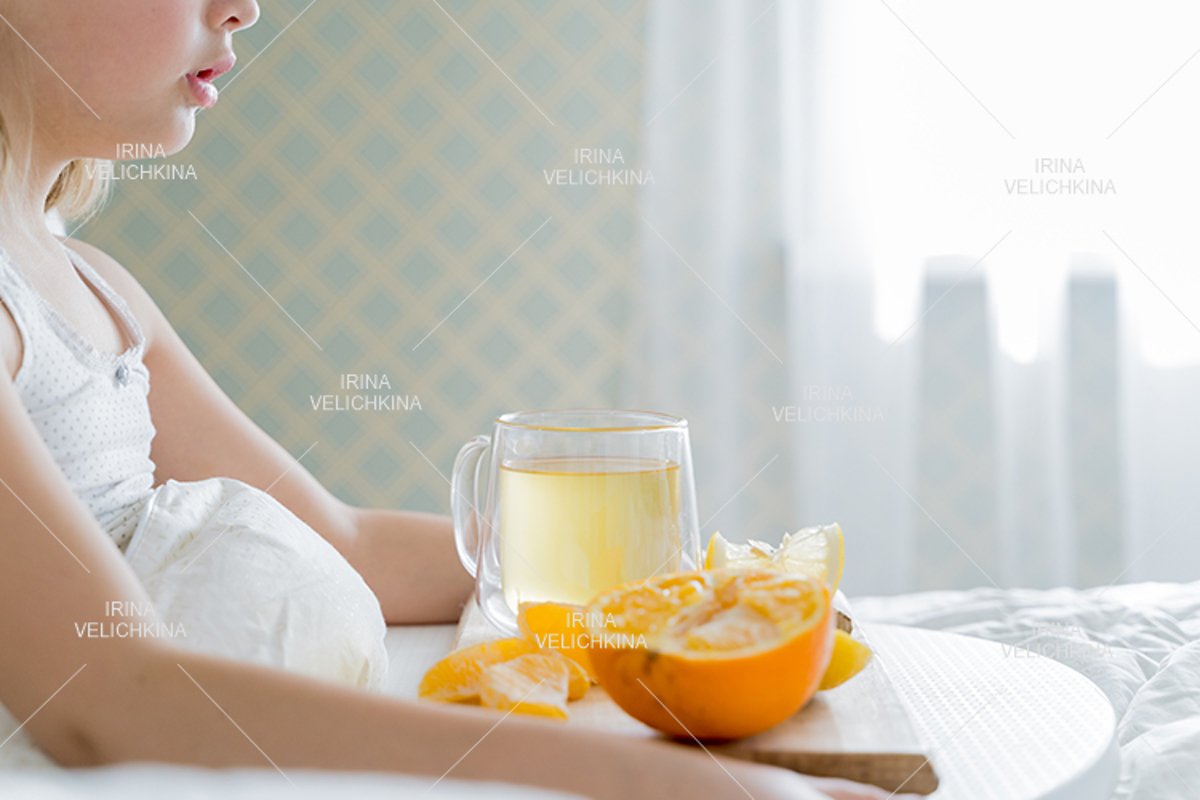 Sick girl in bed. Cup of flu drugs. Tea, orange,lemon,ginger example image 1