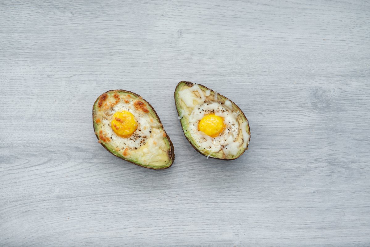 Two eggs baked in avocado on wooden table example image 1