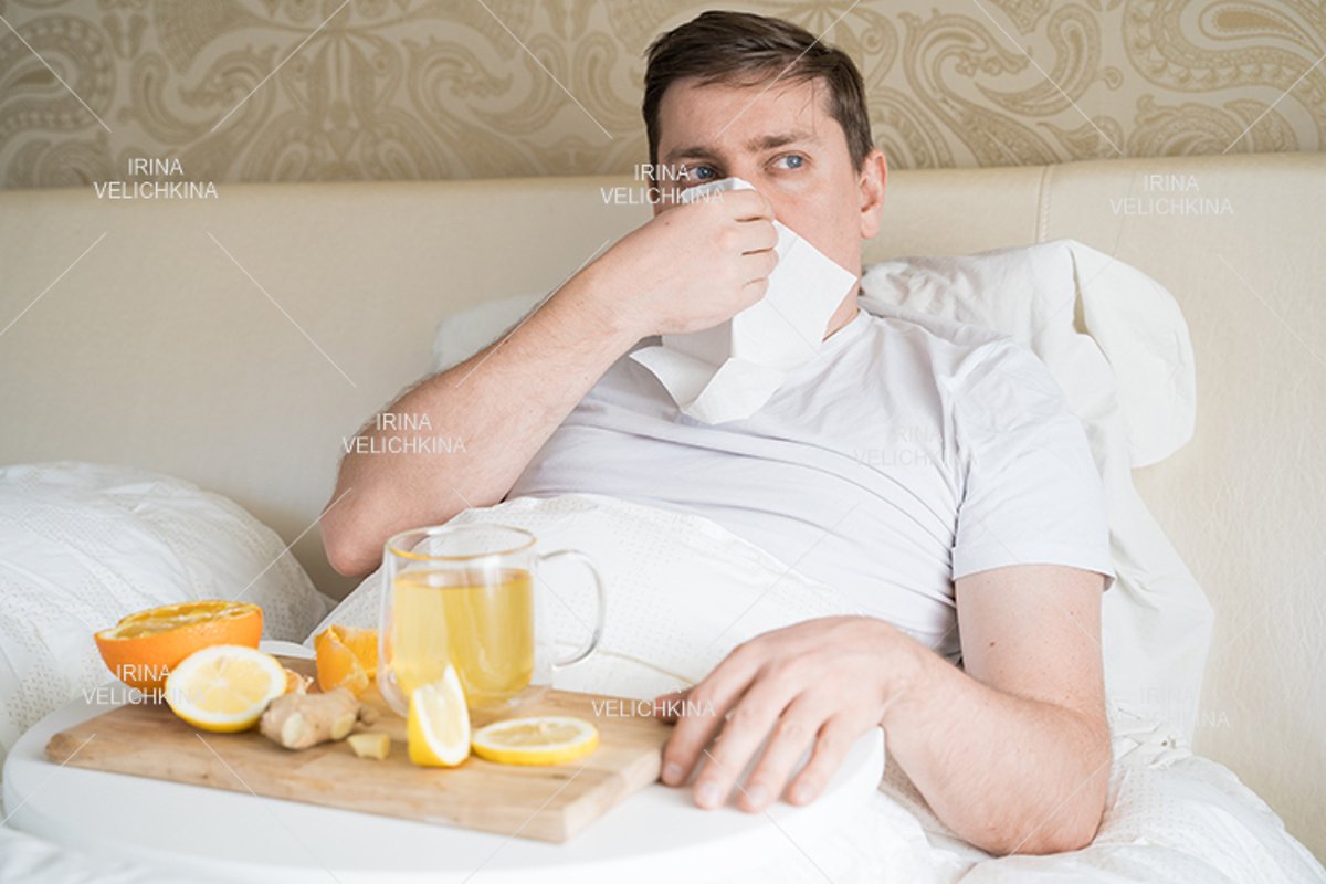Sick man in bed. Cup of flu drugs. Tea, orange,lemon,ginger example image 1