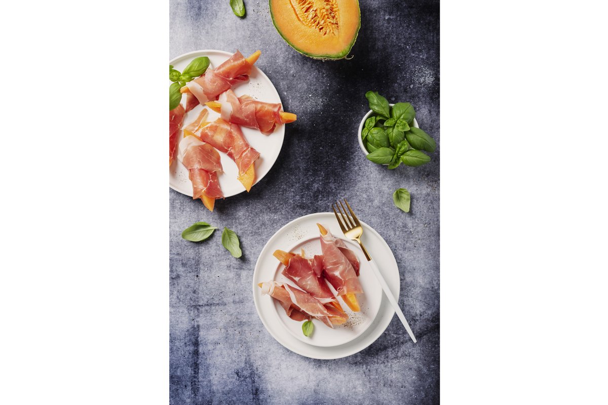 Summer appetizer with sweet melon and ham on dark background example image 1