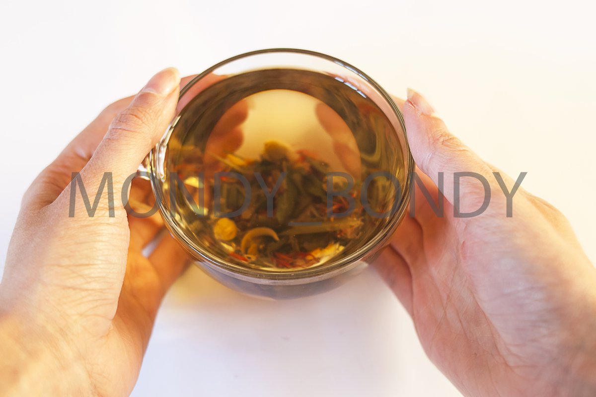 A transparent cup of herbal tea in the hands example image 1
