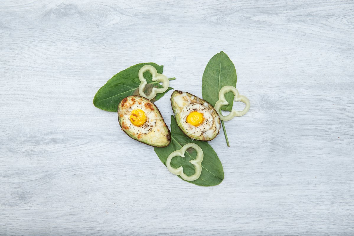 Two Eggs baked in avocado on wooden tabel and green leaves example image 1