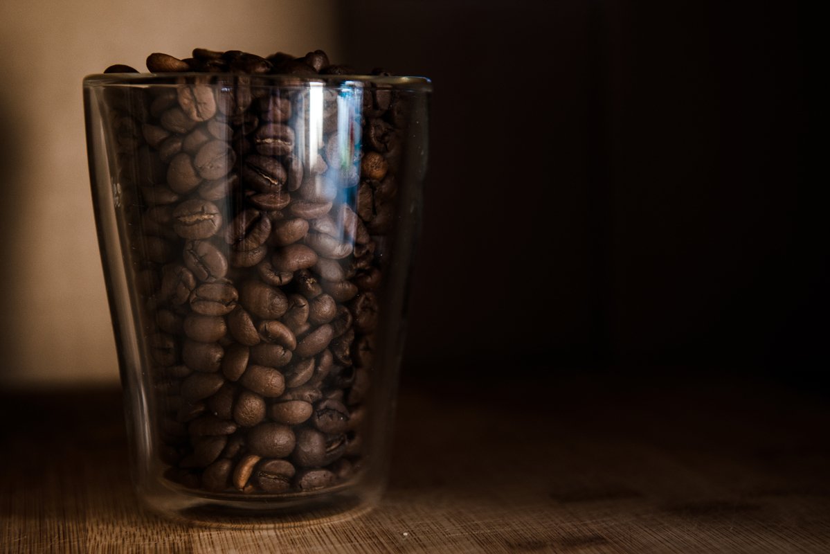 Coffee beans in glass cup on black background example image 1