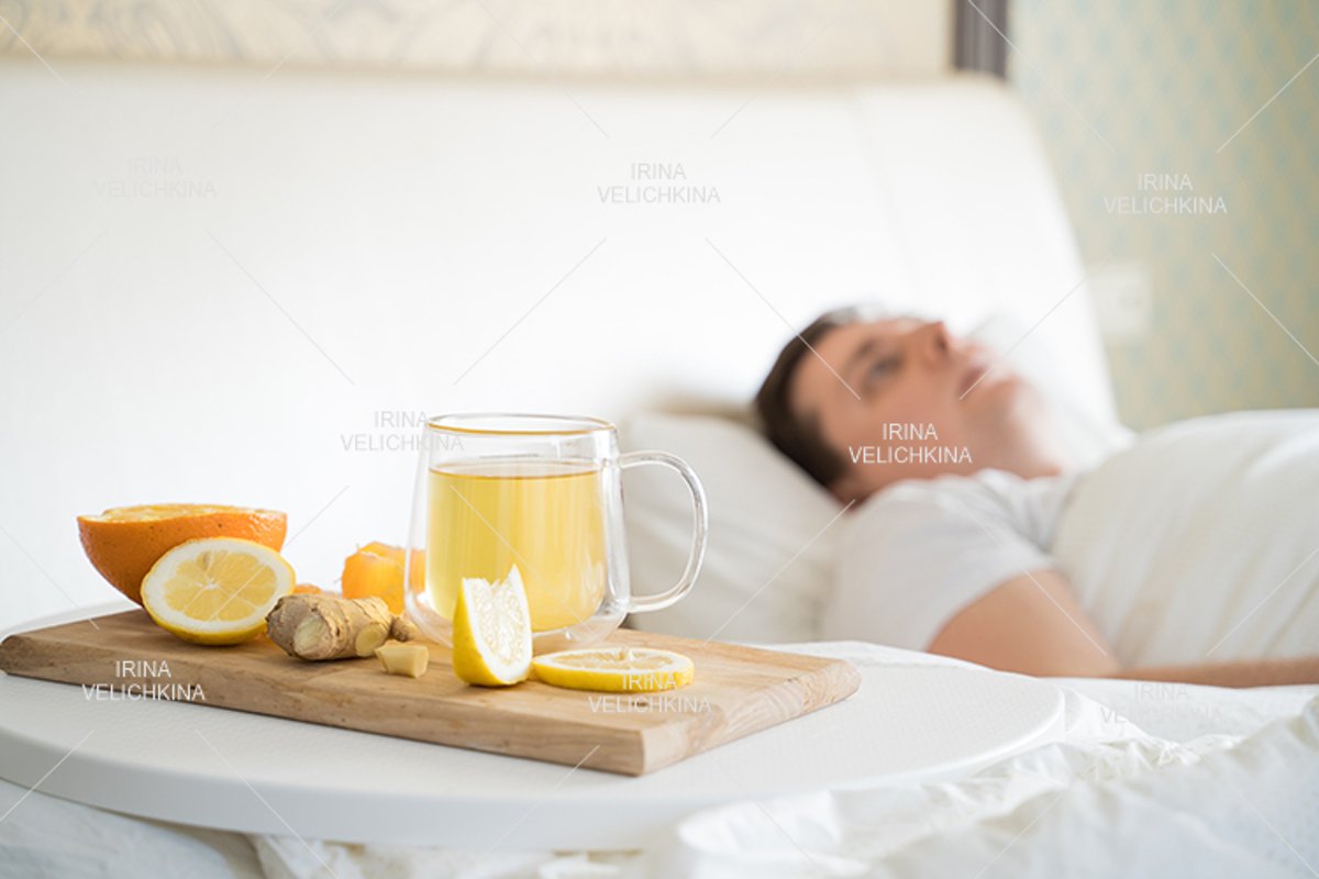Sick man in bed. Cup of flu drugs. Tea, orange,lemon,ginger example image 1