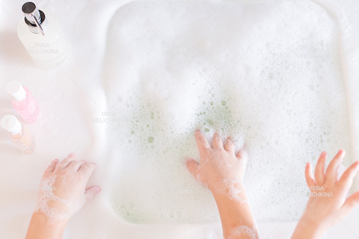 Girls wash their hands in the sink with soap in the foam example image 1