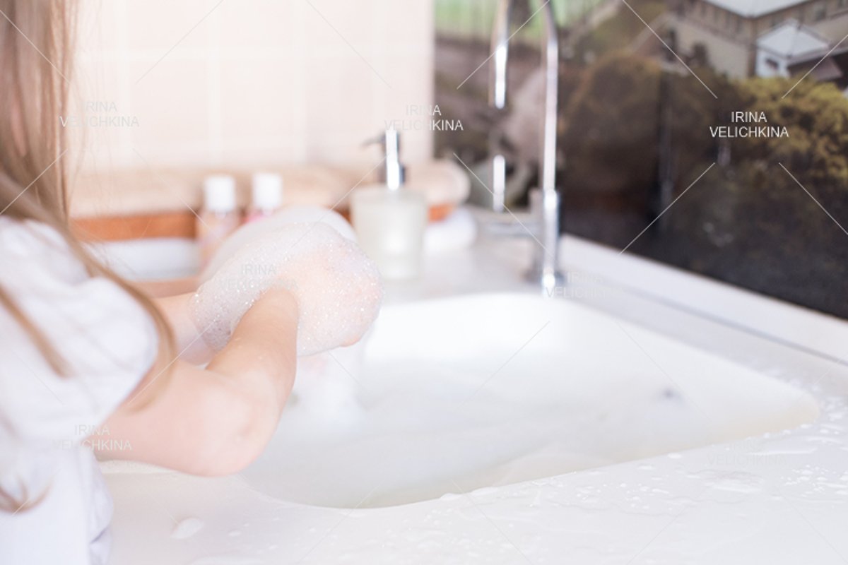 Girls wash their hands in the sink with soap in the foam example image 1