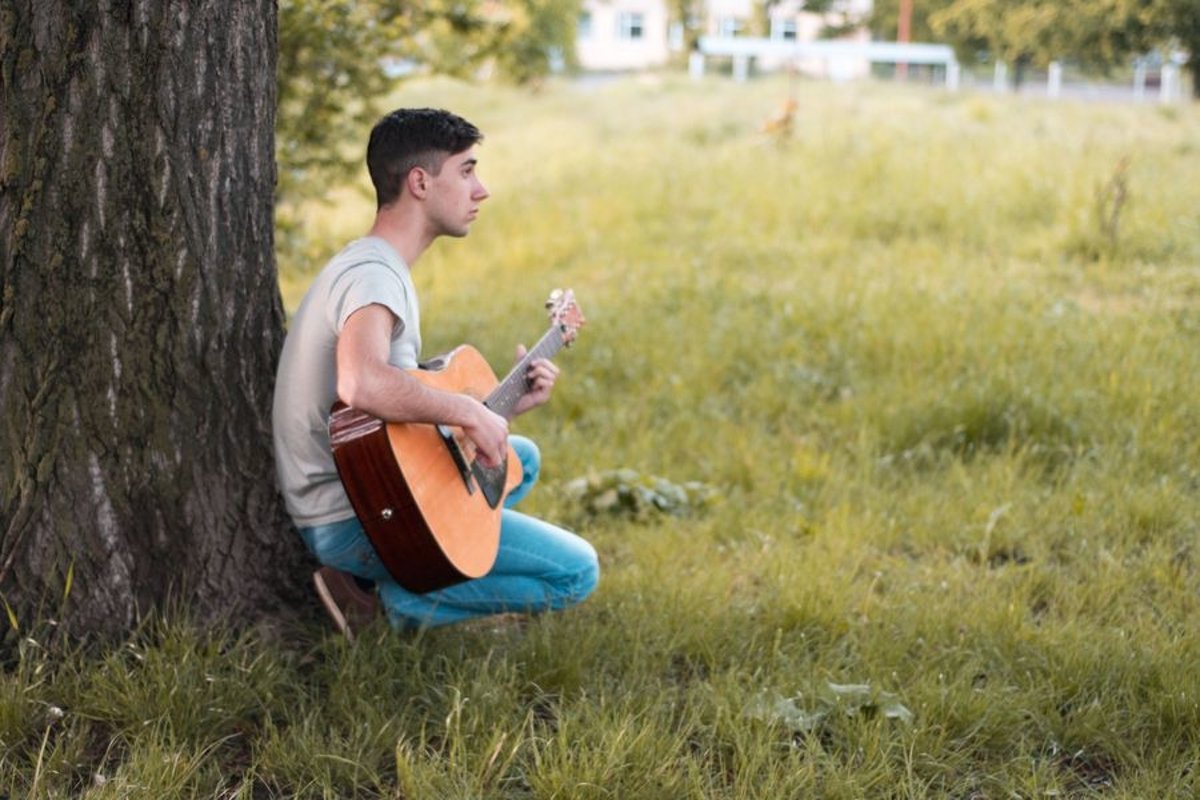 Man plays on acoustic guitar in park example image 1