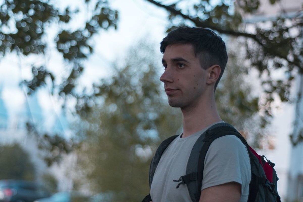 Young caucasian man walks in a park with backpack example image 1