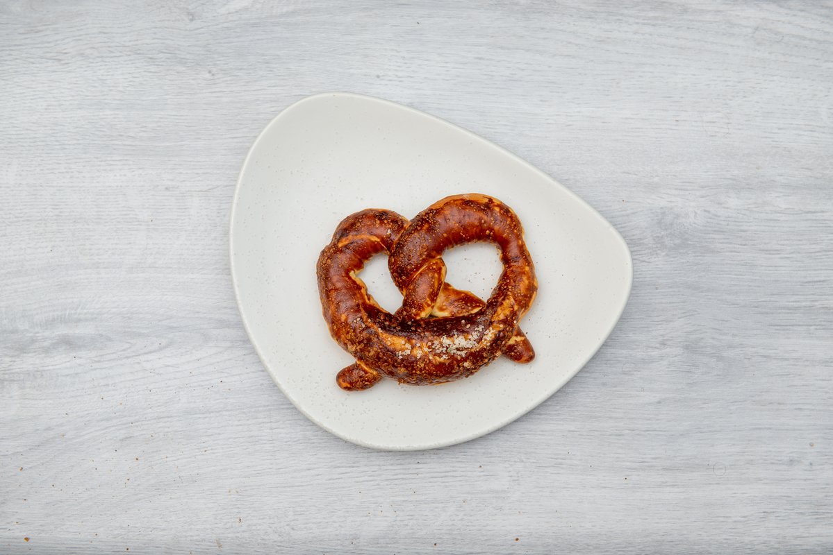 one pretzel on white plate and wooden table example image 1