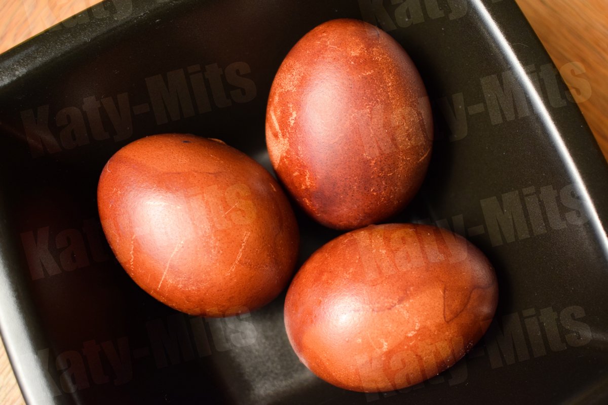 3 naturally colored Easter eggs in black bowl on wooden tabl example image 1