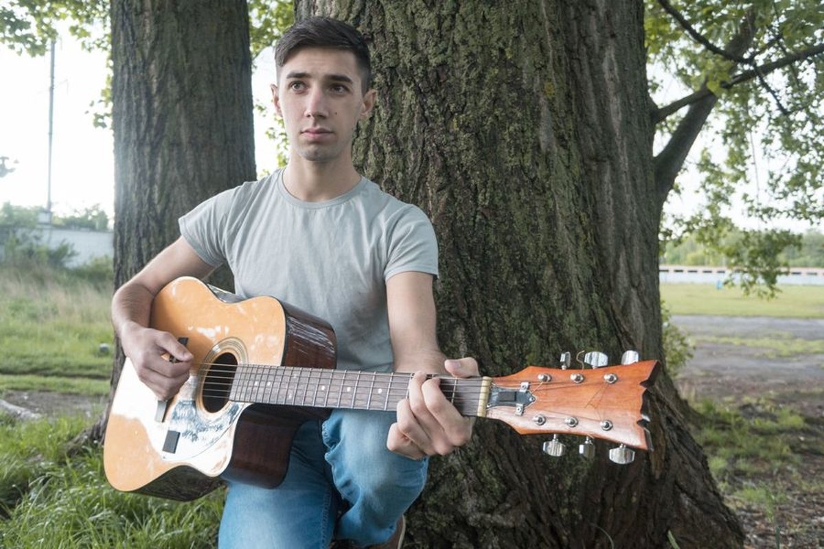 Young caucasian man with guitar in the park example image 1