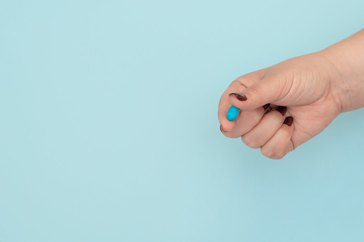 Blue pill on female hand on blue background example image 1