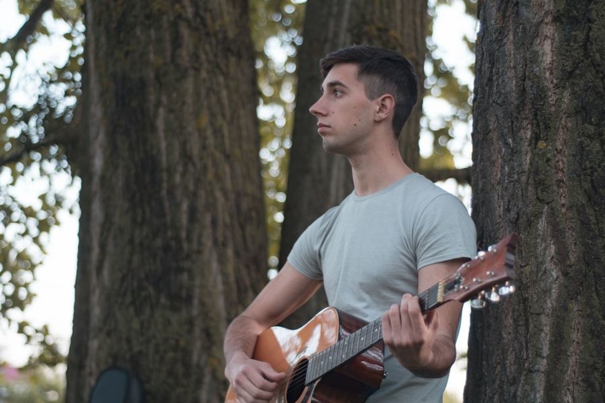 Man plays on acoustic guitar in park example image 1