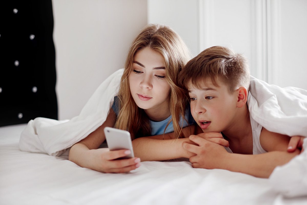 The girl and her younger brother look at photos on the phone example image 1