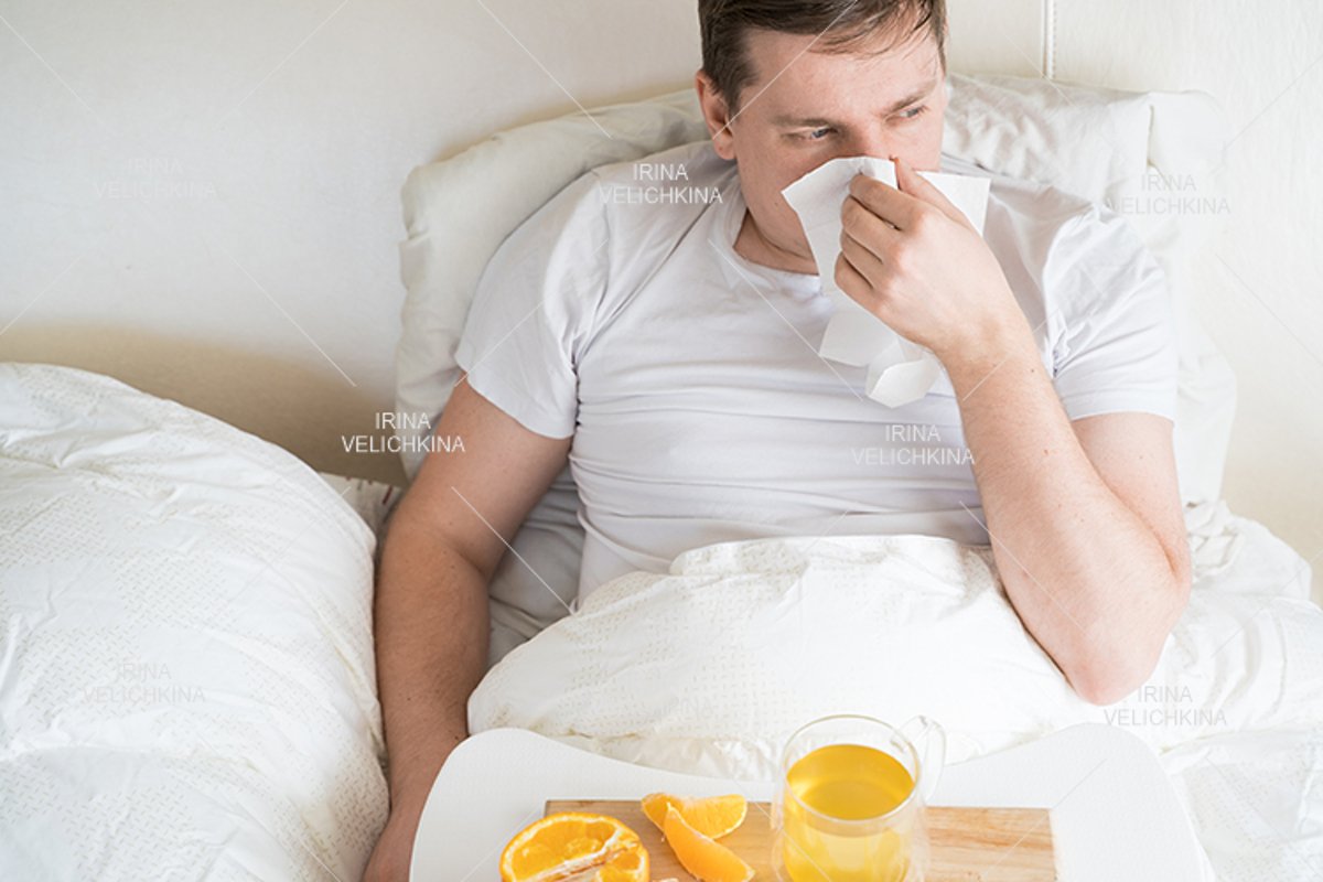 Sick man in bed. Cup of flu drugs. Tea, orange,lemon,ginger example image 1