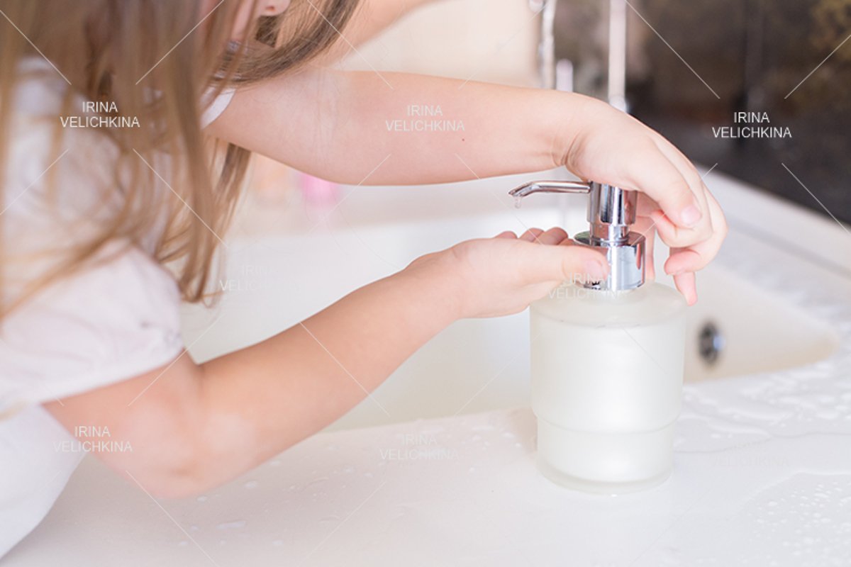 Girls wash their hands in the sink with soap in the foam example image 1