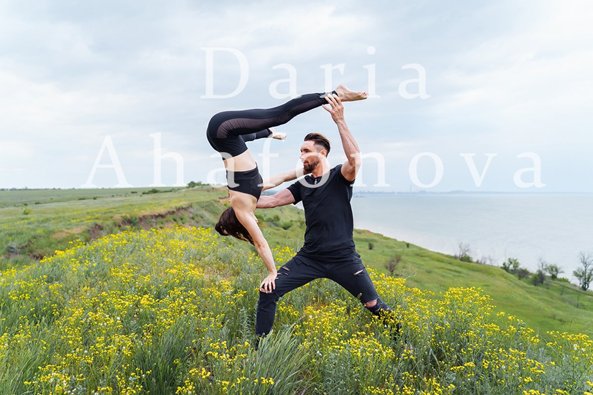 Couple practicing acro yoga poses outdoors outside. example image 1