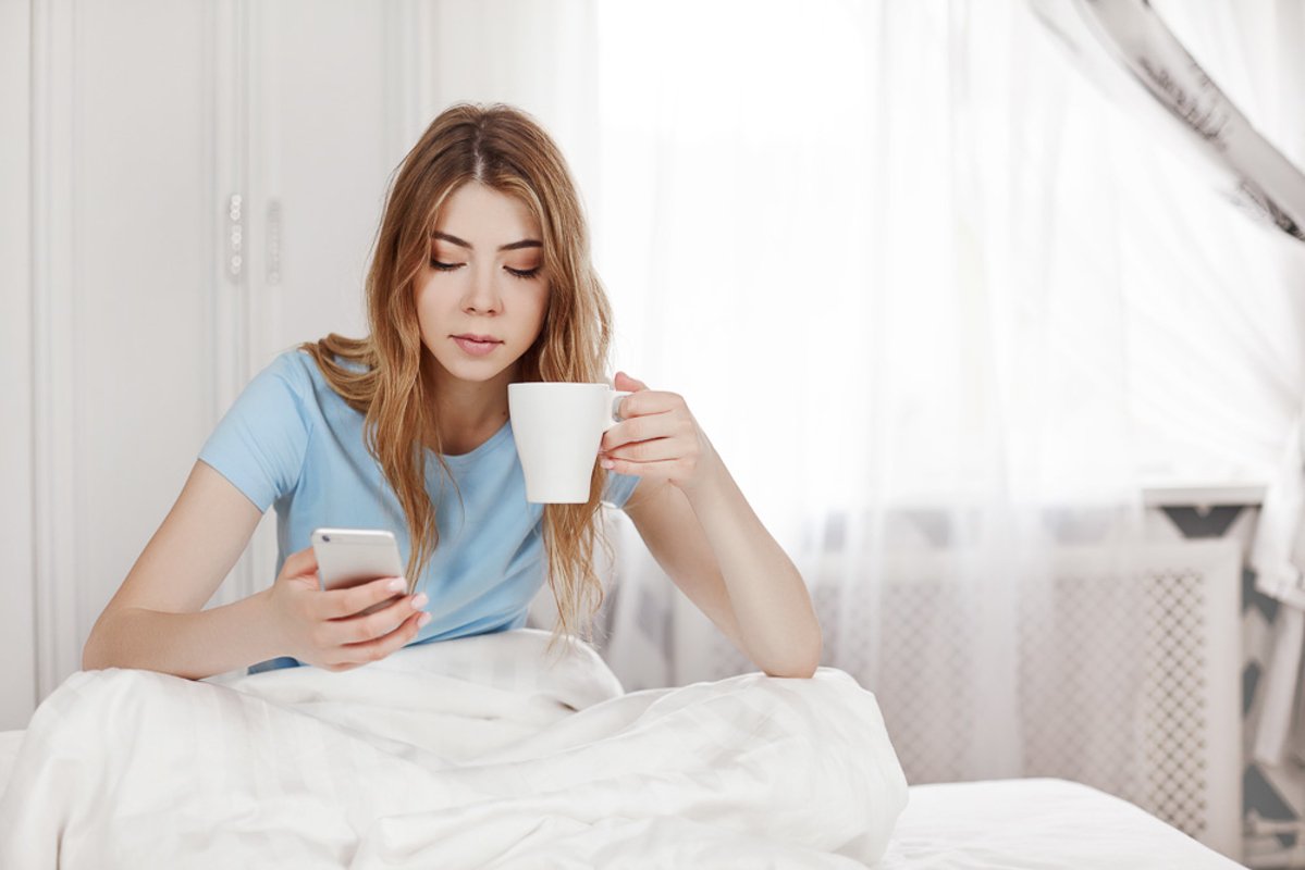 A beautiful relaxed girl is sitting in bed in her pajamas. example image 1