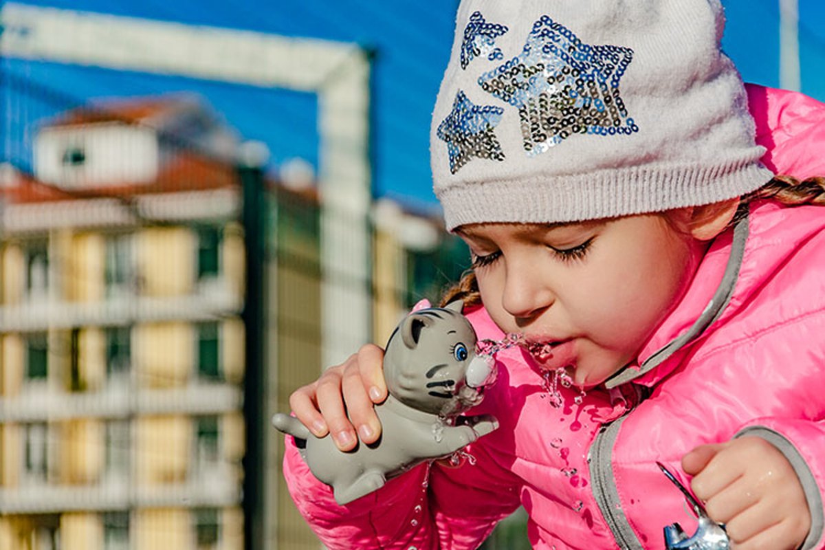 A pre-school girl drinks from a drinking fountain in a park. example image 1