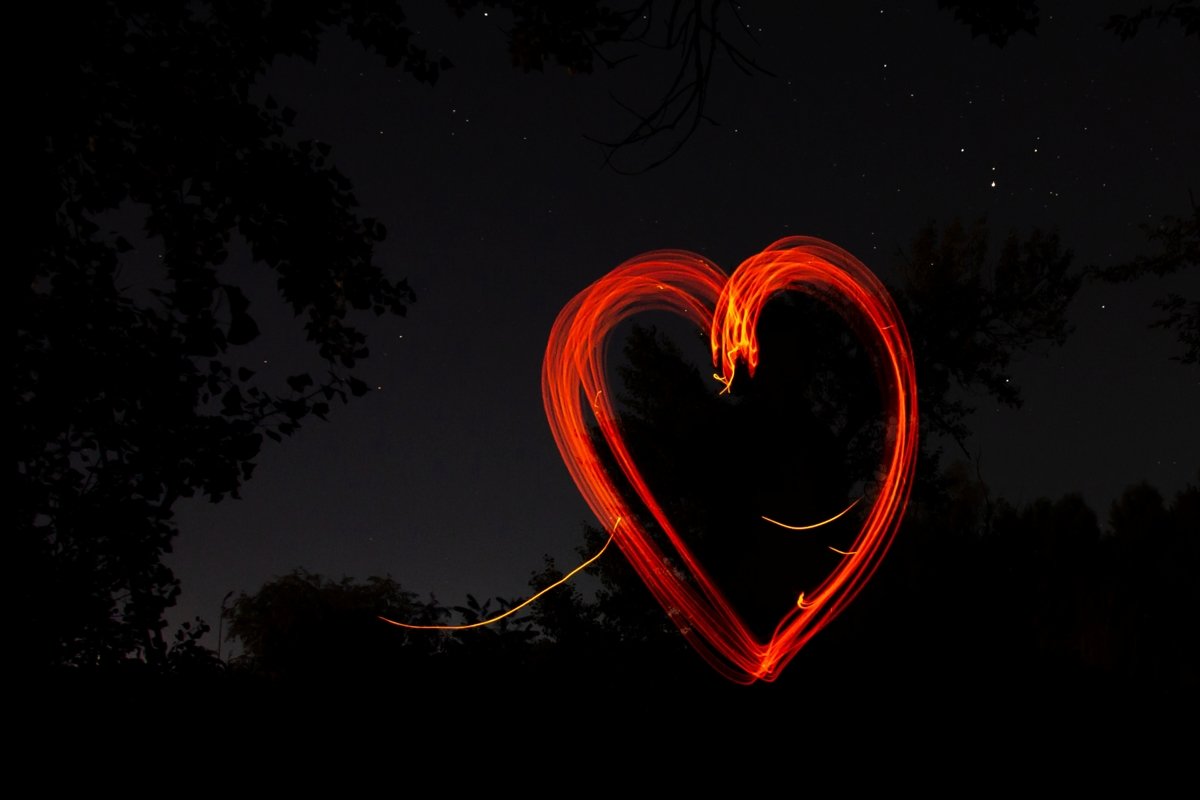 Red heart drawn by fire on black night background example image 1