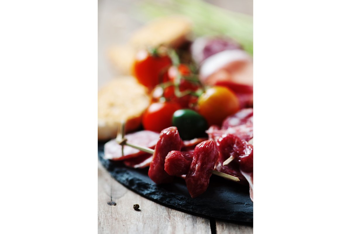 Antipasto with ham, olive and tomato on the wooden table example image 1