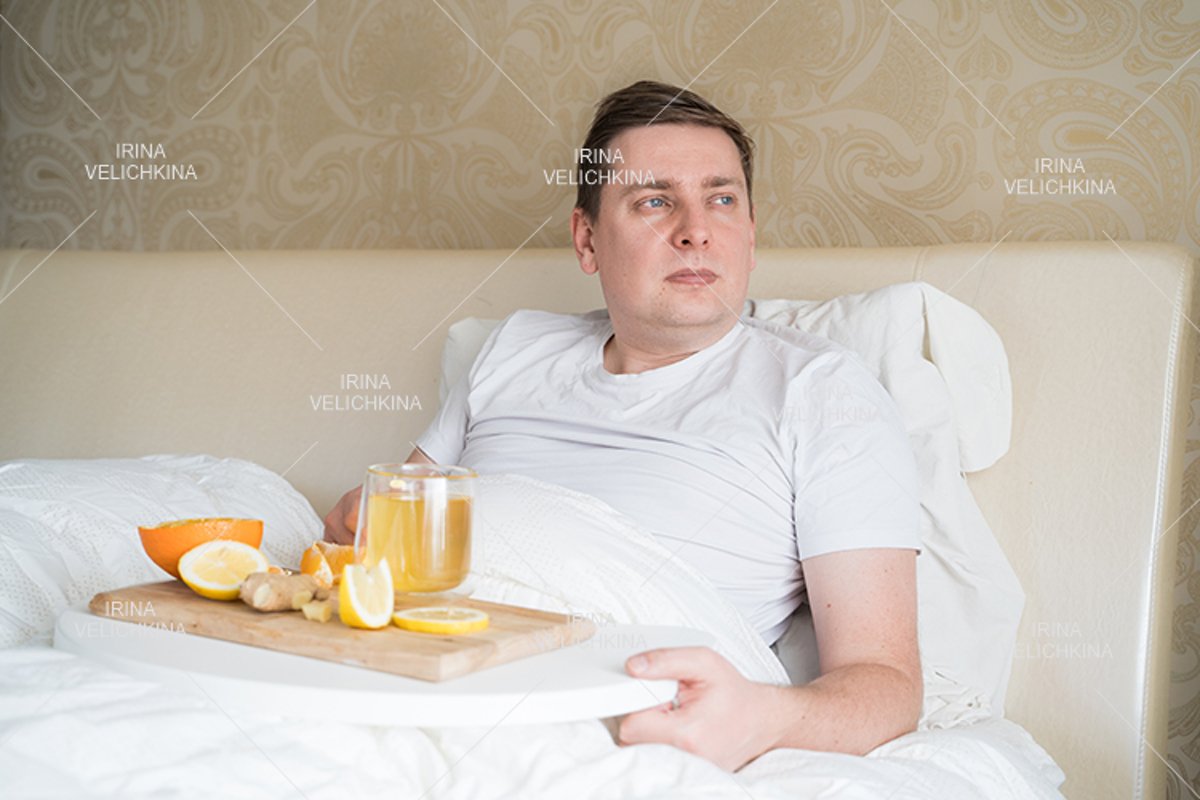 Sick man in bed. Cup of flu drugs. Tea, orange,lemon,ginger example image 1