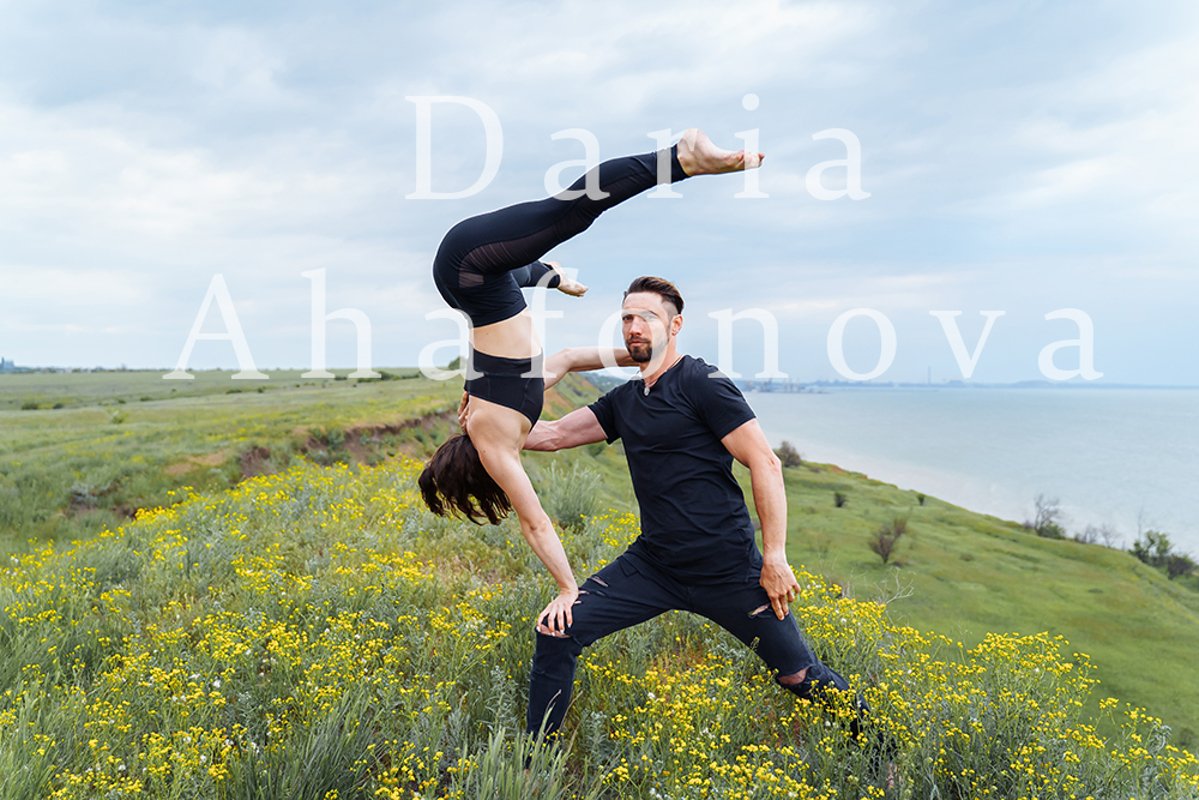 Couple practicing acro yoga poses outdoors outside. example image 1