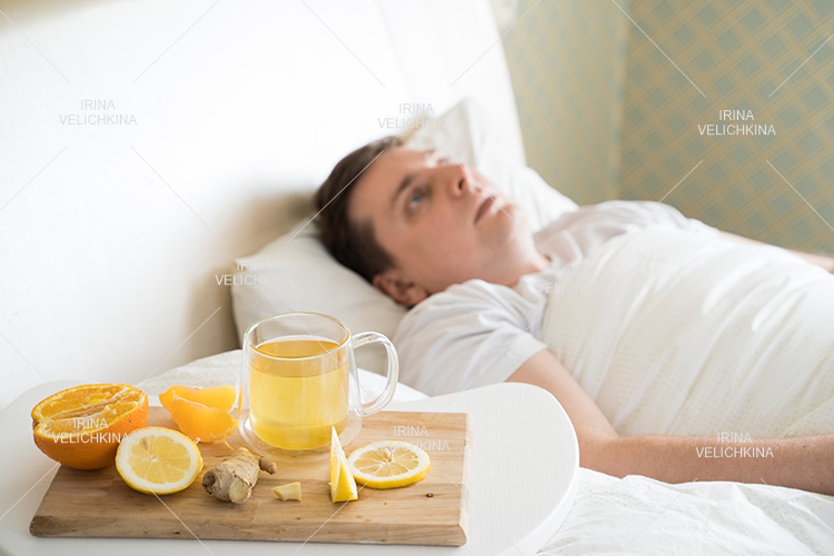 Sick man in bed. Cup of flu drugs. Tea, orange,lemon,ginger example image 1