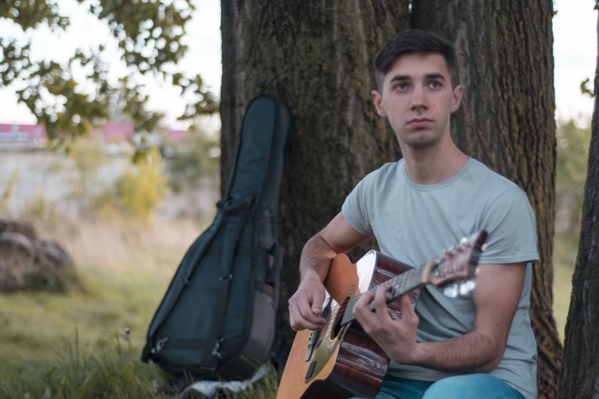 Man plays on acoustic guitar in park example image 1