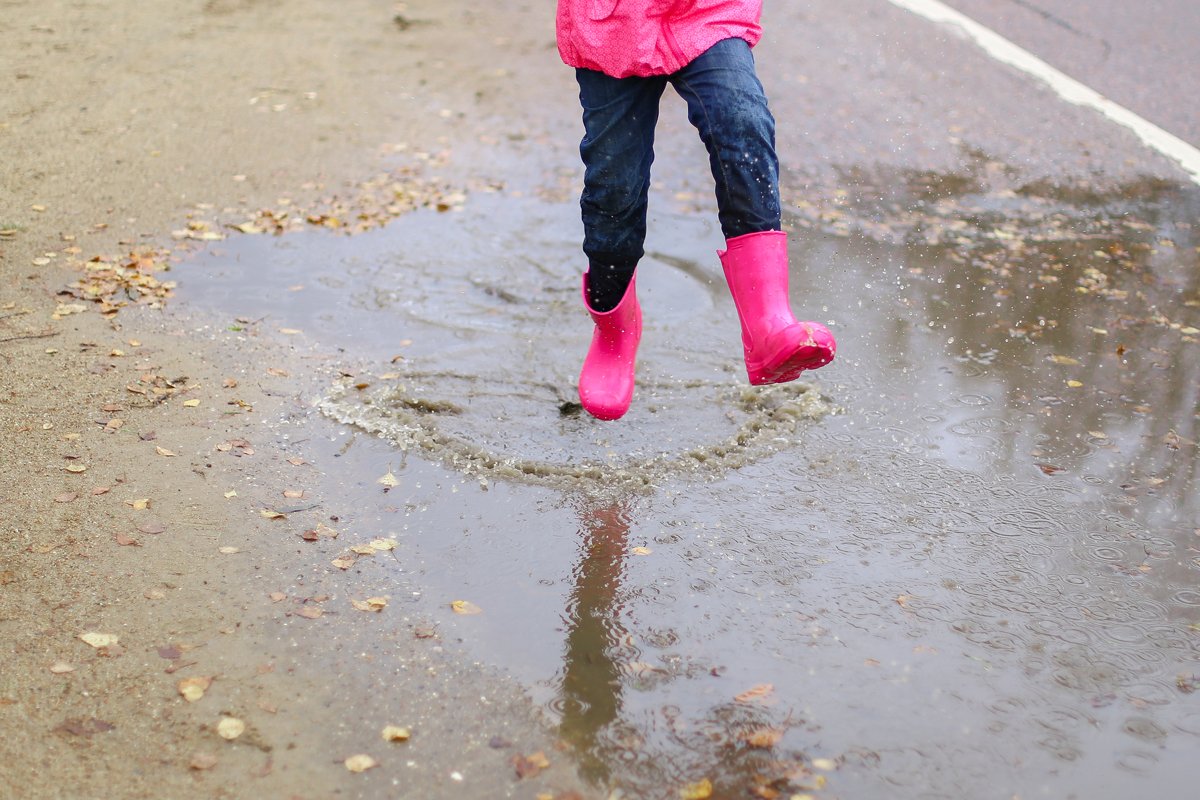 Girl in pink rubber boots jumps through puddle.Spring,autumn example image 1