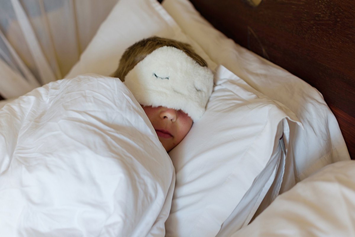 little boy in a sleep mask sleeps in a bed example image 1