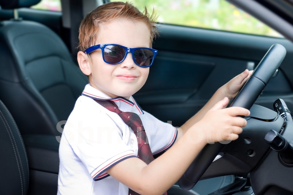 Cute driver. Smilng boy in sunglases in car example image 1