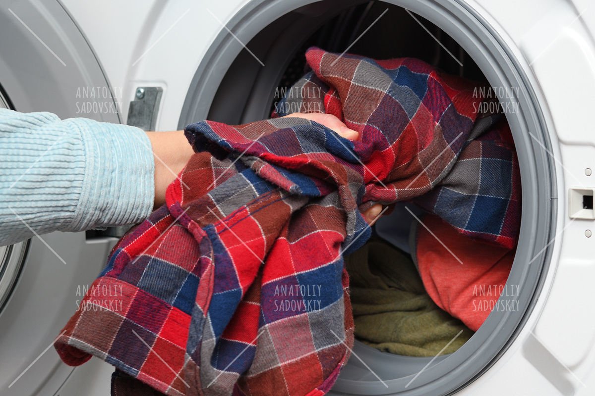 Woman puts clothes in washing machine example image 1