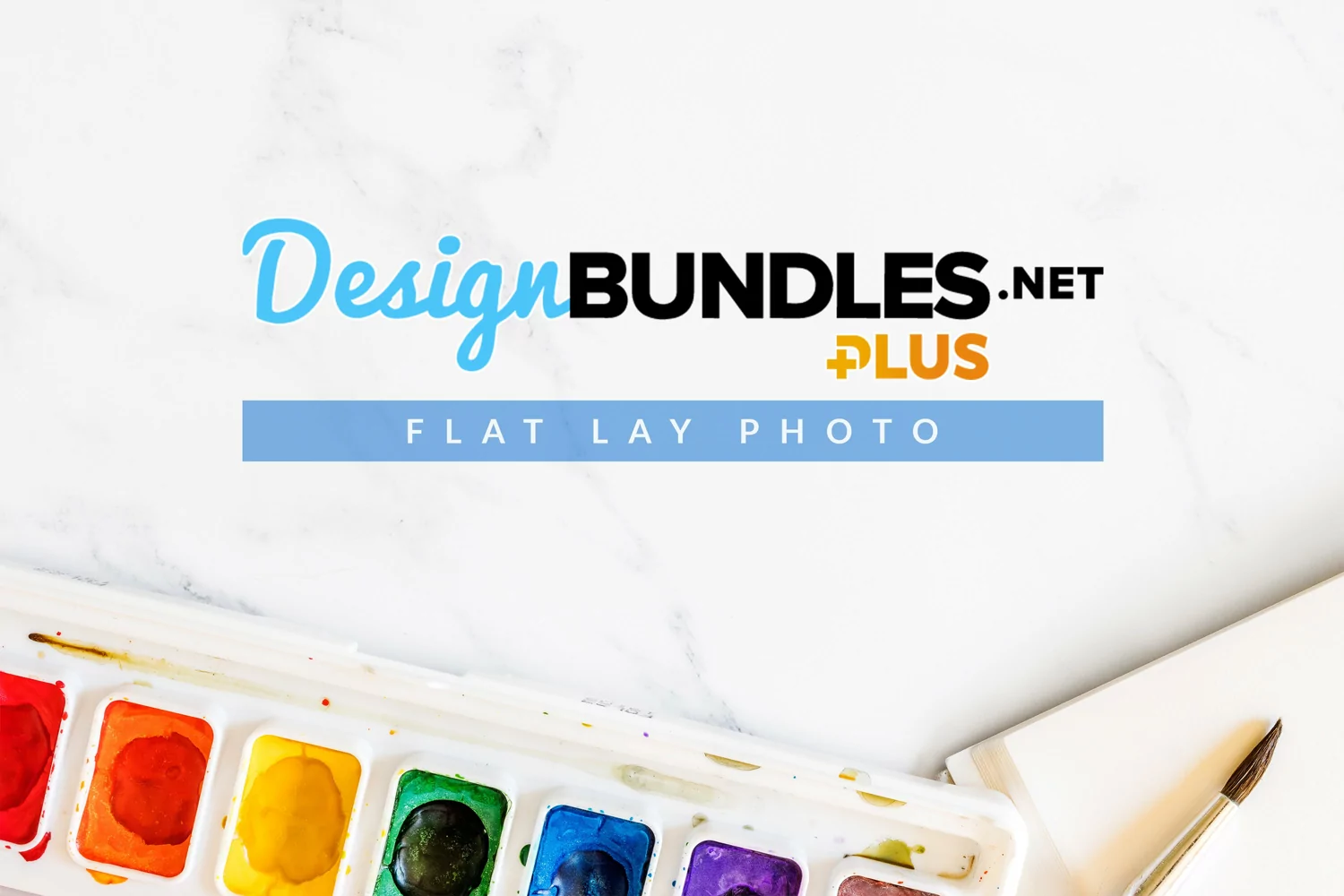 flat lay image of watercolor paint, brush and sketch pad