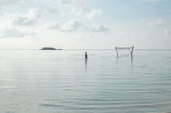 Lonely woman and wooden swing in the middle of sea shallow Product Image 1