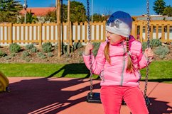 Little girl 5-6 years on a playground swinging on swing. Product Image 1