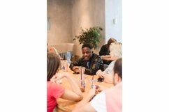 Vertical photo. Black man talking to classmates in a cafe Product Image 1