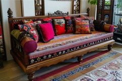 Wooden sofa with carved legs and colorful cushions standing Product Image 1