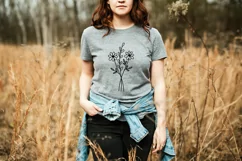 A girl is standing in a field in a gray T-shirt with wildflowers print